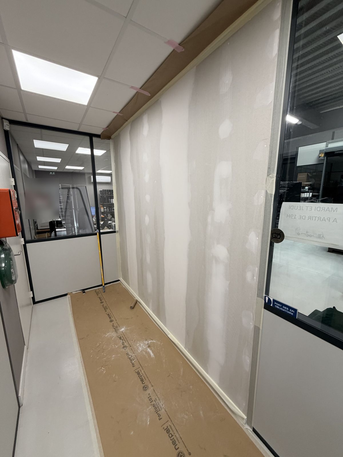 Cloison avant peinture : joints de plaques enduits, sol protégé par une bâche, bords masqués