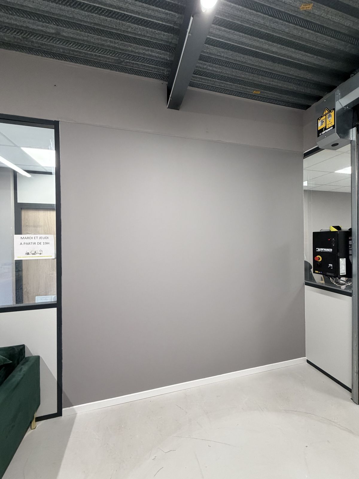 Mur de bureaux peint en gris, sous un plafond industriel